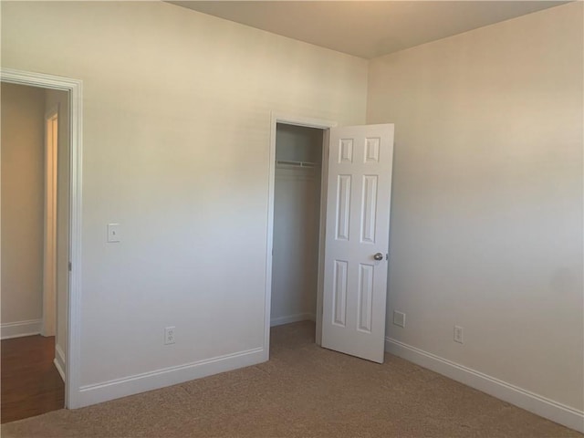 unfurnished bedroom with light colored carpet and a closet