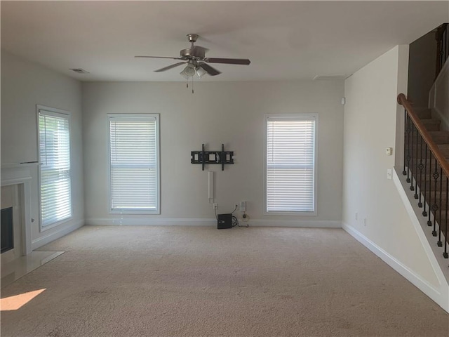 unfurnished living room featuring light colored carpet and ceiling fan