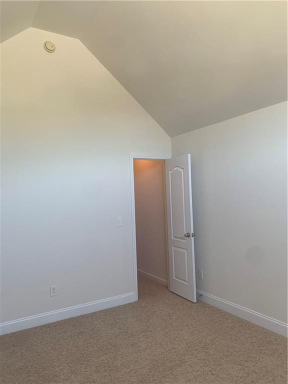 carpeted empty room with lofted ceiling