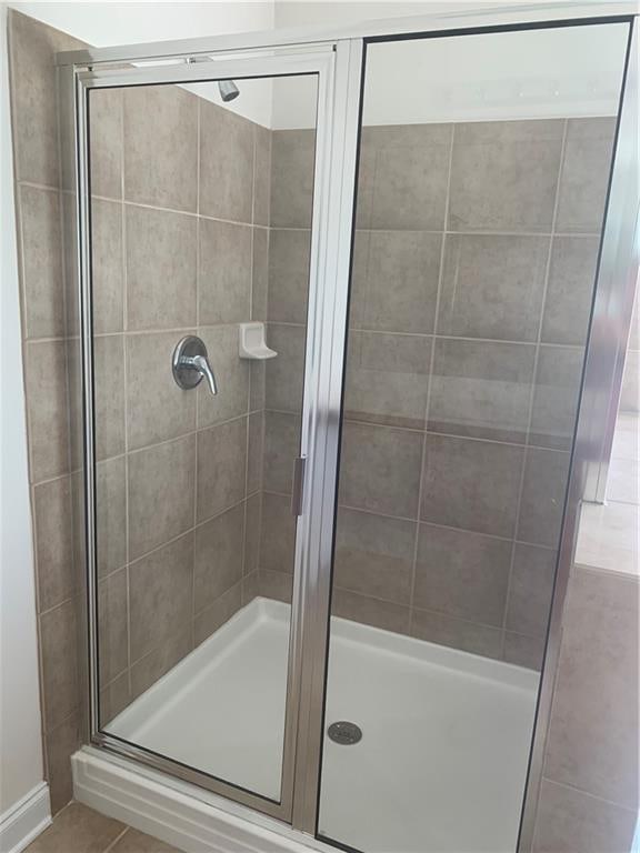 bathroom with tile patterned floors and a shower with door