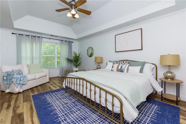 bedroom with ceiling fan, dark hardwood / wood-style flooring, and a raised ceiling