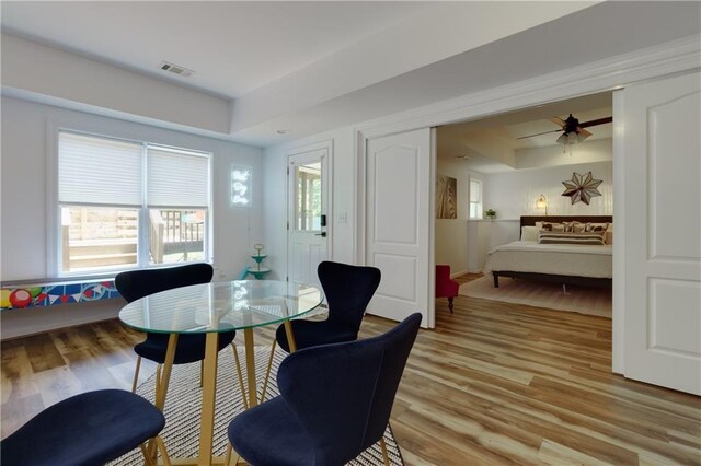 dining room featuring light hardwood / wood-style floors, a raised ceiling, and ceiling fan