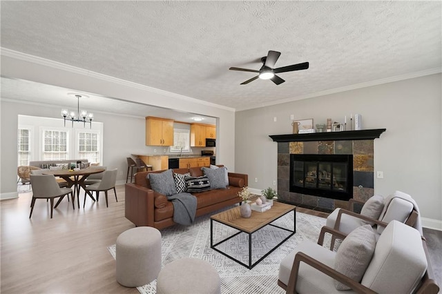 living area featuring a textured ceiling, light wood finished floors, baseboards, and crown molding