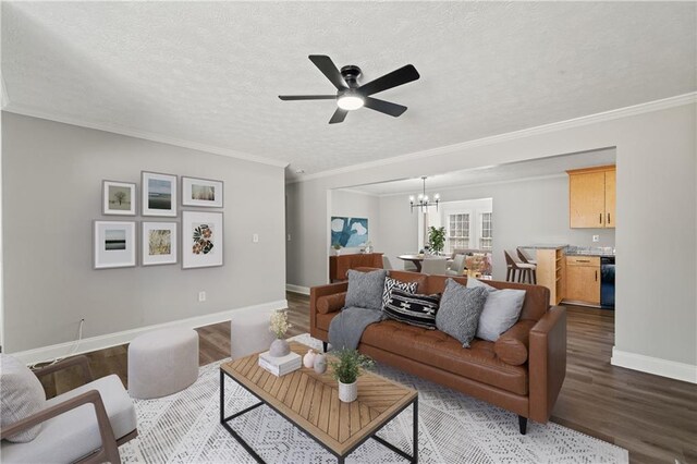 living room featuring a textured ceiling, ceiling fan with notable chandelier, wood finished floors, baseboards, and ornamental molding