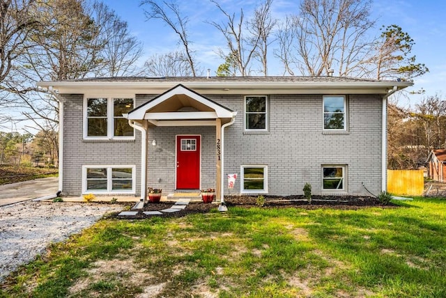 split foyer home with brick siding, a front yard, and fence