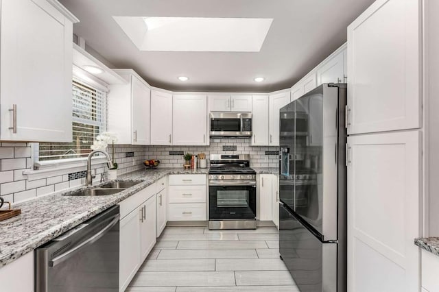 kitchen featuring tasteful backsplash, white cabinetry, stainless steel appliances, and a sink