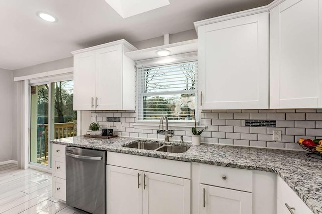 kitchen featuring light stone counters, tasteful backsplash, a sink, and white cabinetry