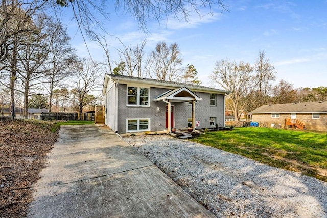 raised ranch with a front yard, brick siding, and fence