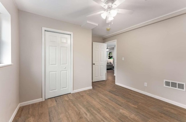 unfurnished bedroom with ceiling fan, wood finished floors, visible vents, baseboards, and a closet