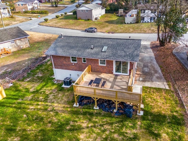 back of house featuring a shingled roof, a residential view, a deck, central AC, and brick siding