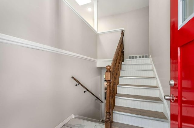 stairway with marble finish floor, visible vents, and baseboards