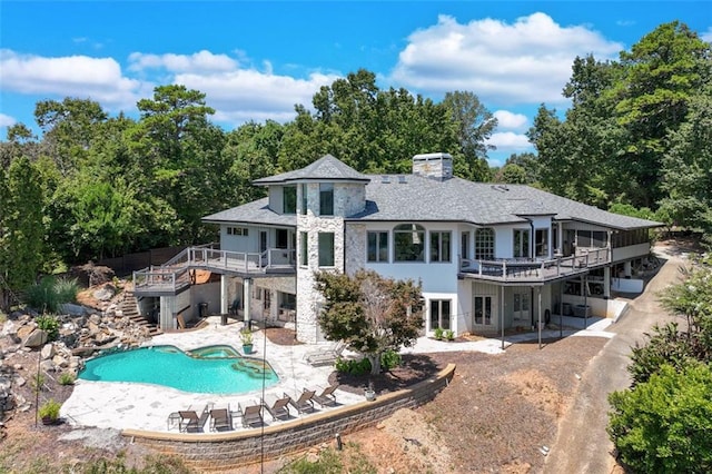 back of house with a wooden deck, stone siding, a patio, and stairs