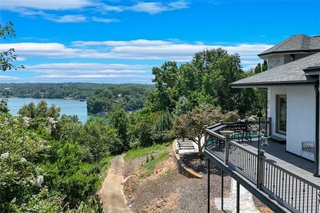 exterior space featuring a view of trees and a deck with water view