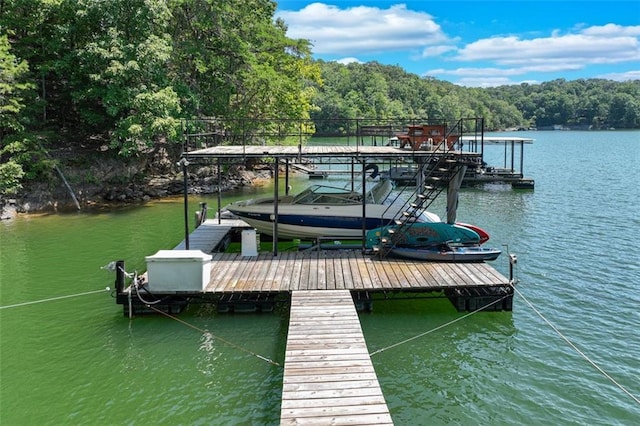 view of dock with a view of trees, boat lift, and a water view