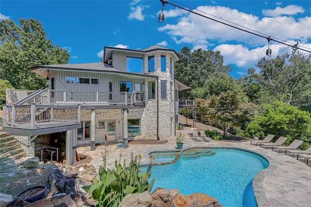 rear view of property with stairway, a deck, board and batten siding, a pool with connected hot tub, and a patio
