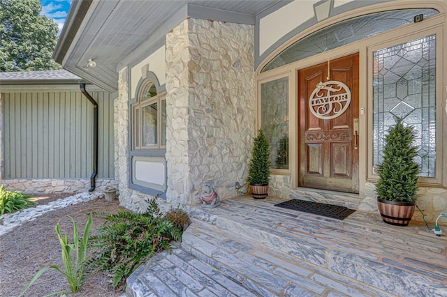 view of exterior entry with stone siding and board and batten siding