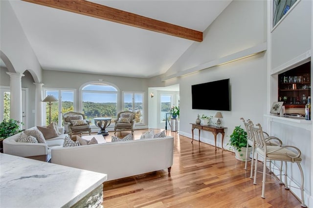 living area featuring high vaulted ceiling, light wood-type flooring, ornate columns, and beamed ceiling