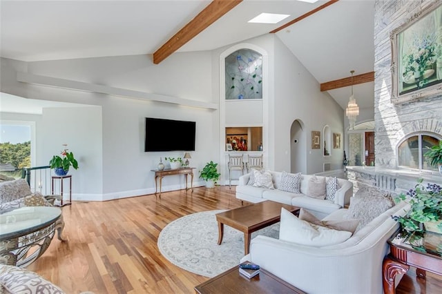 living room with a fireplace, high vaulted ceiling, light hardwood / wood-style flooring, and beam ceiling