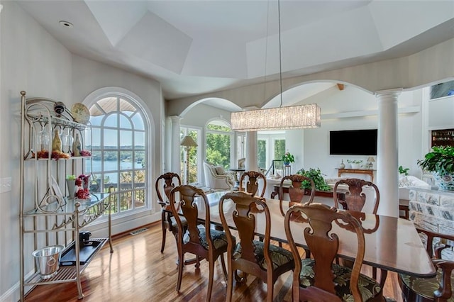 dining room with wood finished floors, arched walkways, and ornate columns