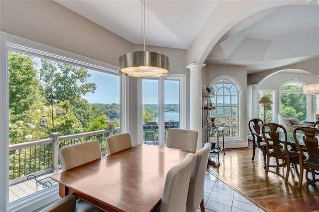 dining area featuring arched walkways, lofted ceiling, tile patterned flooring, and decorative columns
