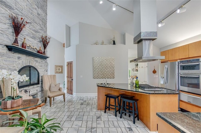 kitchen with a warming drawer, high vaulted ceiling, track lighting, a breakfast bar, and appliances with stainless steel finishes