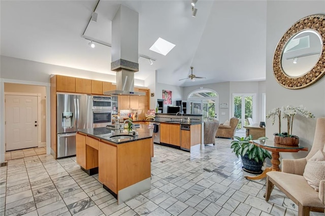 kitchen featuring high vaulted ceiling, a skylight, track lighting, and a center island with sink