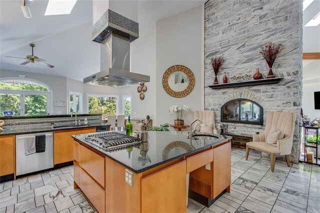 kitchen with an island with sink, dark stone counters, stainless steel appliances, and a sink
