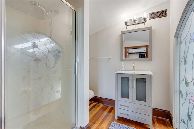 bathroom with an enclosed shower, vaulted ceiling, hardwood / wood-style floors, and toilet