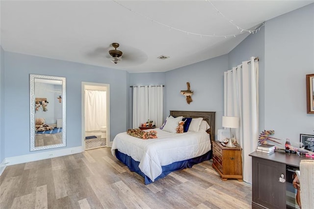 bedroom with connected bathroom, light wood-type flooring, ceiling fan, baseboards, and visible vents