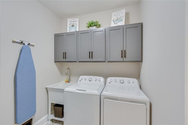 laundry room featuring washing machine and clothes dryer, baseboards, and cabinet space