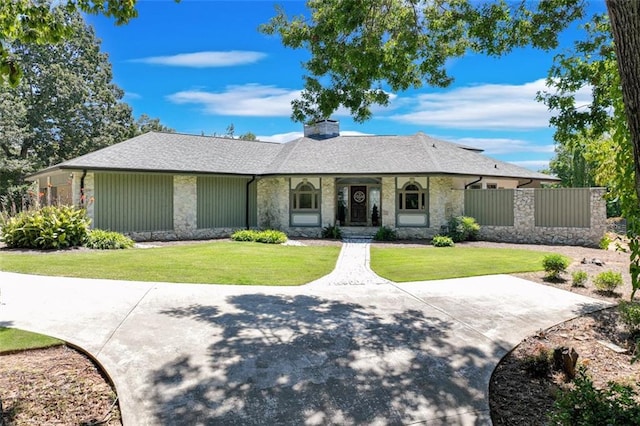 ranch-style house featuring stone siding, a chimney, fence, and a front yard