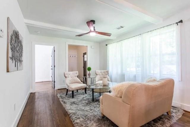 sitting room featuring plenty of natural light, dark hardwood / wood-style floors, beamed ceiling, and ceiling fan