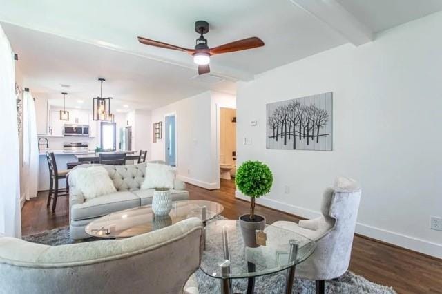 living room featuring ceiling fan, dark wood-type flooring, and beamed ceiling