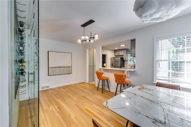 dining area with light wood-type flooring and a chandelier