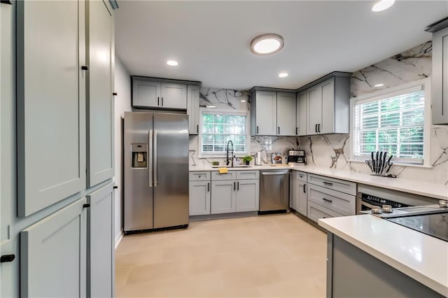 kitchen with backsplash, a wealth of natural light, sink, and stainless steel appliances