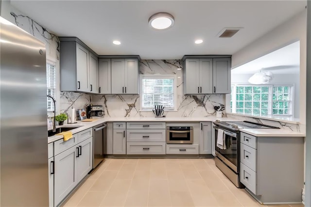 kitchen with gray cabinetry, stainless steel appliances, and tasteful backsplash