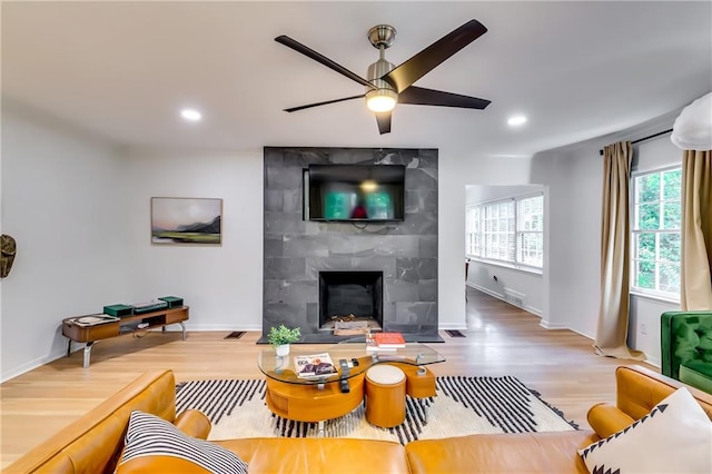 living room with ceiling fan, wood-type flooring, and a fireplace