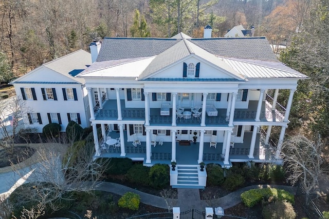 view of front of property featuring covered porch, roof with shingles, a chimney, and a balcony