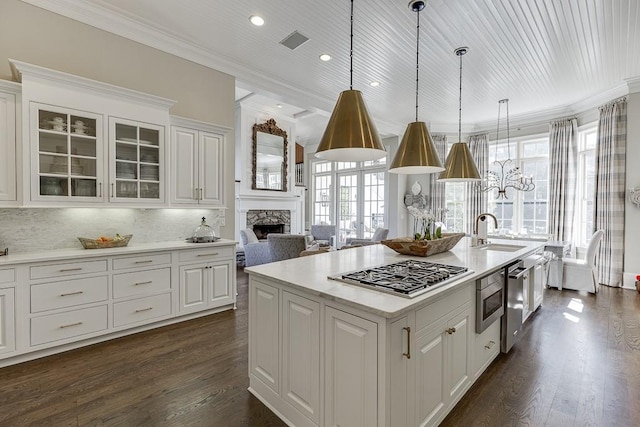 kitchen featuring dark wood-style flooring, a sink, white cabinets, stainless steel gas stovetop, and crown molding