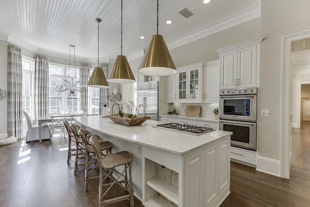 kitchen featuring ornamental molding, dark wood-style flooring, a kitchen island with sink, stainless steel appliances, and white cabinetry