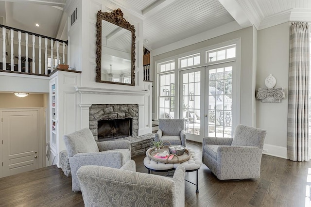 living room featuring a stone fireplace, ornamental molding, french doors, beamed ceiling, and dark wood finished floors