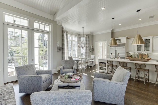 living room featuring visible vents, dark wood finished floors, crown molding, and a chandelier