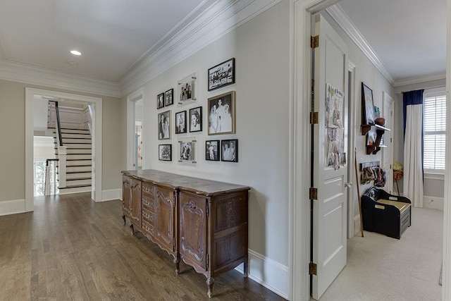 corridor with stairs, ornamental molding, wood finished floors, and baseboards