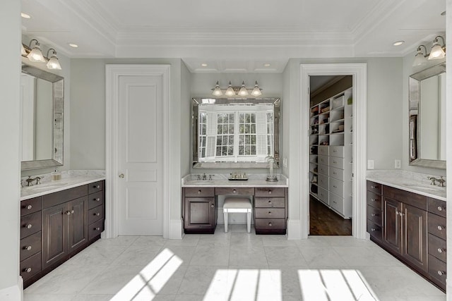 bathroom with a sink, two vanities, a walk in closet, and crown molding