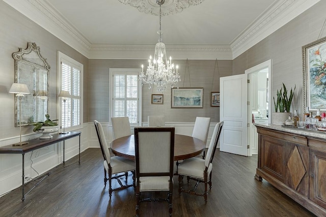 dining area featuring dark wood-style floors, ornamental molding, a decorative wall, and an inviting chandelier