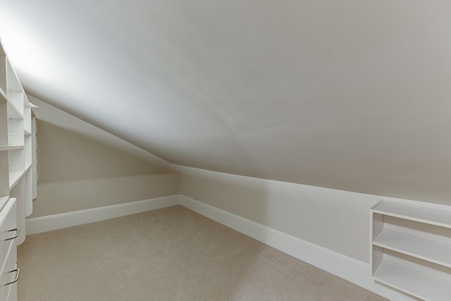 additional living space with baseboards, lofted ceiling, and light colored carpet