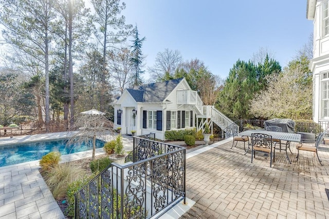 outdoor pool with a patio area, stairs, grilling area, and outdoor dining space