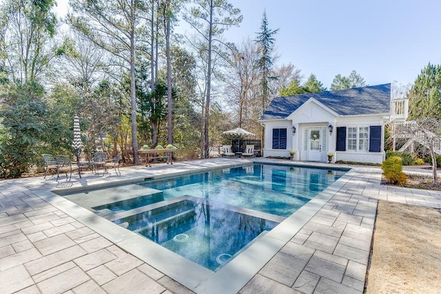 view of pool with an outbuilding, a patio, an exterior structure, and a pool with connected hot tub