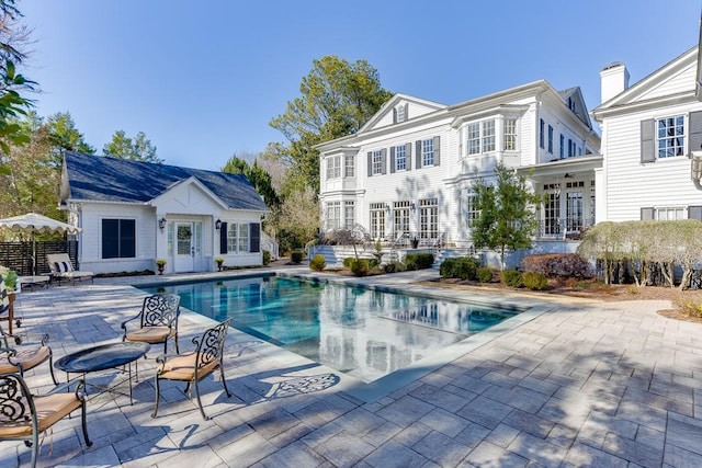 back of house with french doors, a patio, an outdoor pool, an outdoor structure, and a storage structure