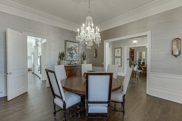 dining area featuring dark wood-style floors, ornamental molding, a wainscoted wall, and a decorative wall